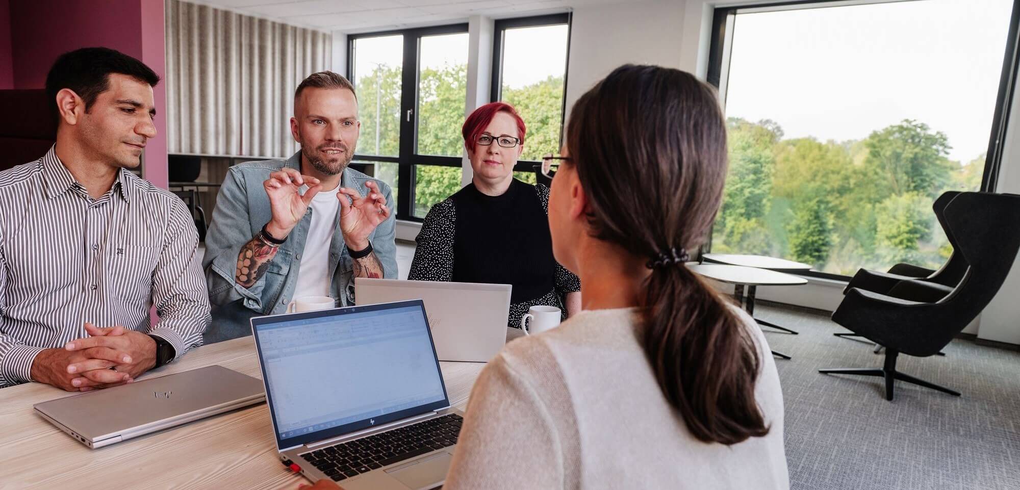 3 Mitarbeiter*innen der IT-Abteilung der Hanseatic Bank diskutieren mit der UX-Expertin über eine neue Funktion